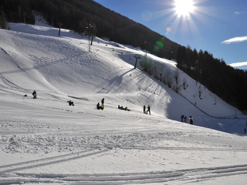 Weite Piste im Gegenlicht der Sonne über dem Bergrücken.